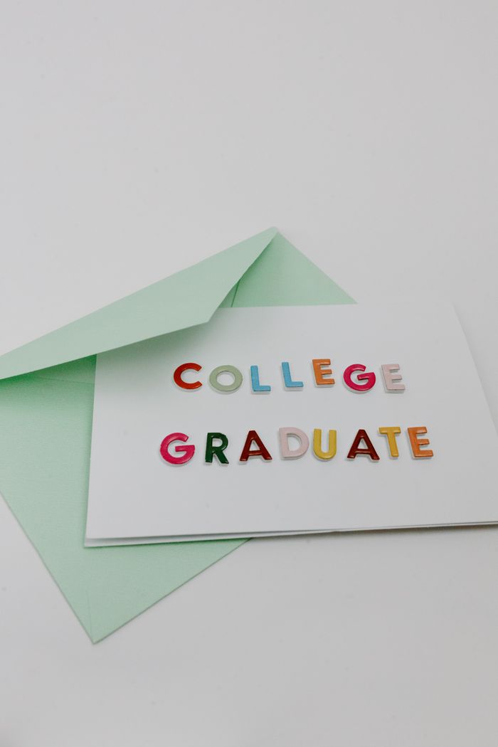 Top view of a colorful college graduate greeting card with envelope on a white surface.